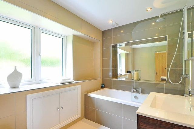 Kleines, helles Badezimmer mit Badewanne, Waschtisch und Unterschrank