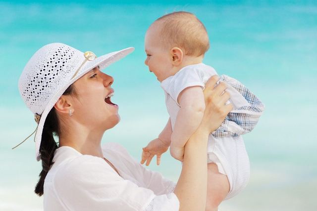 Mutter hebt lachend ihr Baby hoch