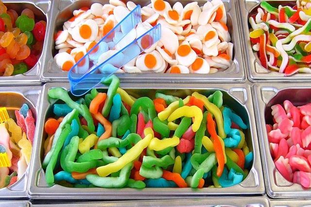 Bunte Fruchtgummis in mehreren Behältern an einer Süßwarentheke