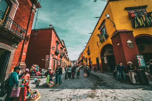 Bunte Kolonialhäuser und Passanten in einer Altstadtgasse in Mexiko